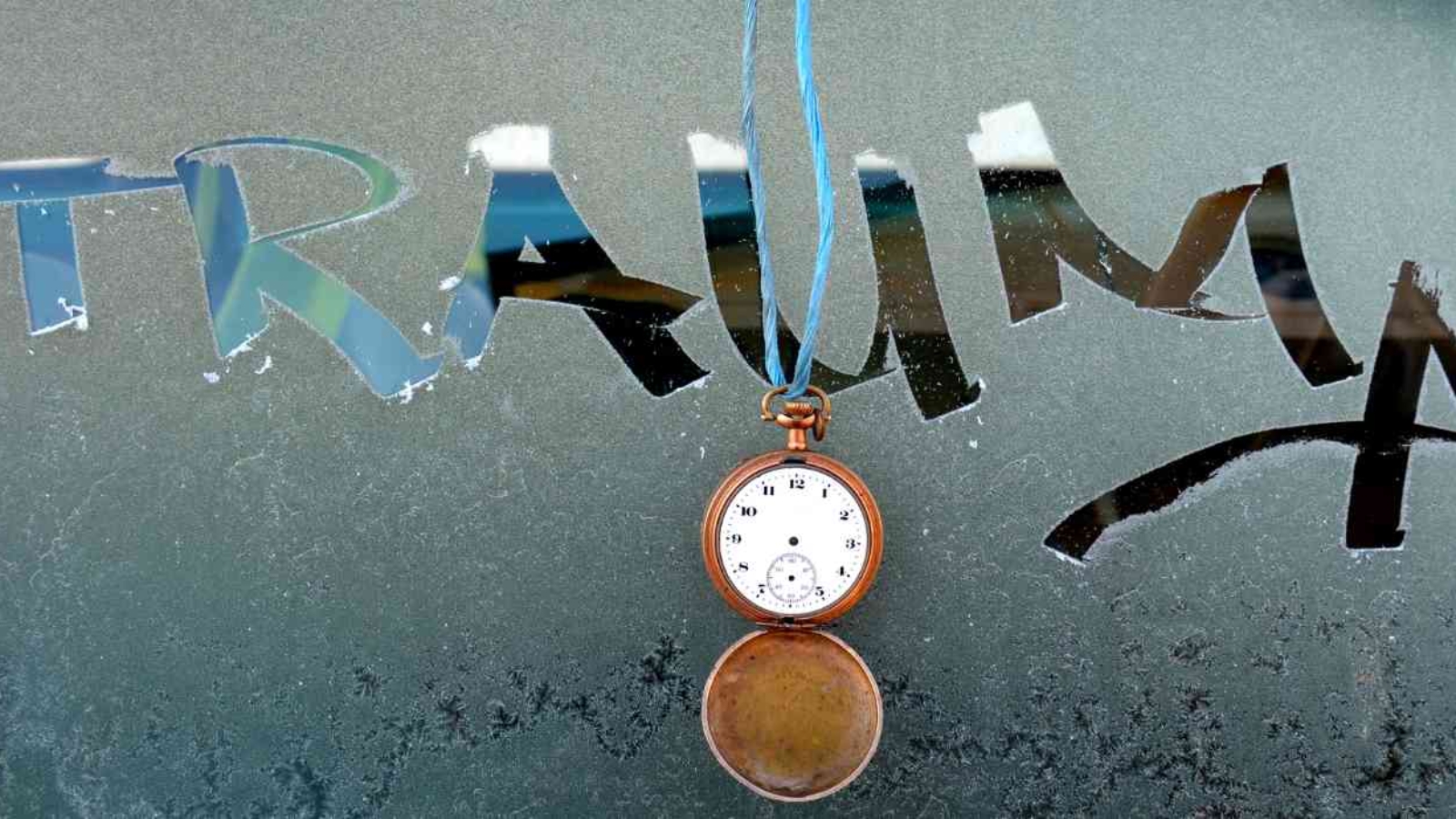 a-word-trauma-written-on-a-frosti-window-with-a-hand-clock-hanging